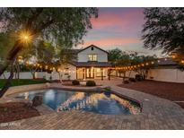 Backyard pool and patio with outdoor lighting create a relaxing evening ambiance at 20412 W Thayer St, Buckeye, AZ 85396