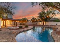 Sparkling pool and brick patio with string lights and fire pit offer outdoor relaxation at 20412 W Thayer St, Buckeye, AZ 85396