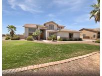Two-story home boasts lush green lawn, mature trees, and well-maintained landscaping at 5501 W Whispering Wind Dr, Glendale, AZ 85310