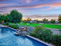 Beautiful pool with rock waterfall feature overlooking a lush green golf course at sunset at 9878 N 79Th Pl, Scottsdale, AZ 85258