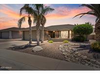 Charming home featuring desert landscaping, palm trees, and a warm sky at sunset at 11025 E Nichols Ave, Mesa, AZ 85209