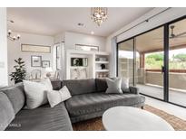 Bright living room with a gray sofa, white pillows, and a large window view to the patio at 12642 N Mountainside Dr # B, Fountain Hills, AZ 85268