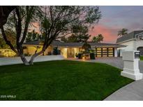 Charming single-story home with a lush green lawn and a stylish, modern garage door at 26 W Morten Ave, Phoenix, AZ 85021