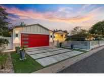 Beautiful home exterior with red garage door, modern driveway, and manicured front yard at sunset at 3429 E Coolidge St, Phoenix, AZ 85018