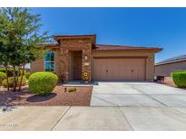 Charming home featuring stone accents, a two-car garage, and meticulously manicured landscaping at 41825 W Mesquite Rd, Maricopa, AZ 85138