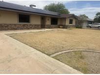 Charming single-story home featuring stone accents, desert landscaping, and modern solar panels at 5542 W Monte Cristo Ave, Glendale, AZ 85306