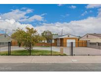 Charming single-story home with a large, fenced front yard and a sunny, blue sky backdrop at 6837 W Camelback Rd, Phoenix, AZ 85033