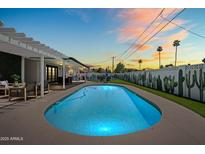 Backyard pool at dusk offers a refreshing escape, enhanced by desert landscaping and covered patio at 8315 E Devonshire Ave, Scottsdale, AZ 85251
