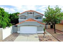 Charming two-story home featuring a white garage door, desert landscaping, and a classic red-tiled roof at 909 W San Mateo Ct, Gilbert, AZ 85233