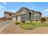 Landscaped front yard with grass and decorative stone, leading to a lovely home with a three-car garage at 1405 S Honeysuckle Cir, Gilbert, AZ 85296