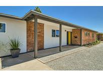 Charming single-story home featuring a brick facade, yellow front door, and desert landscaping at 1930 E Missouri Ave, Phoenix, AZ 85016
