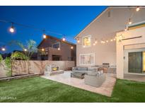 Outdoor living space featuring a stone fireplace, built-in grill and comfortable patio furniture under string lights at 22259 N 102Nd Ln, Peoria, AZ 85383