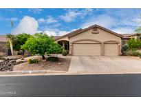 Tan home featuring a three car garage, desert landscaping, and a beautiful blue sky above at 3460 N Stone Gully St, Mesa, AZ 85207