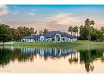 Stunning exterior view of luxury home with waterfront access, lush landscaping, and sunset reflections on a serene lake at 5 E Oakwood Hills Dr, Chandler, AZ 85248