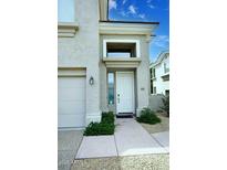 Inviting front entrance with a white door and a well-manicured landscape leading to a two car garage at 8180 E Shea Blvd # 1075, Scottsdale, AZ 85260