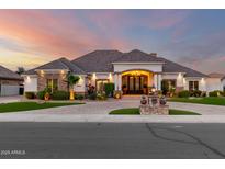 Stunning home featuring stone accents, manicured landscaping, and a grand entrance under a colorful sunset at 23465 S 202Nd St, Queen Creek, AZ 85142