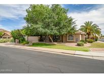 Charming single-story home featuring lush landscaping, mature trees, and well-manicured lawn at 2405 E Lynwood Cir, Mesa, AZ 85213