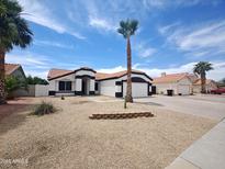 Charming single-story home featuring a tile roof, desert landscaping and an attached garage with driveway at 9231 W Grovers Ave, Peoria, AZ 85382