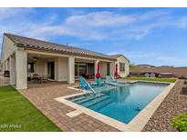Backyard pool area featuring brick pavers, a built-in pool and several deck chairs under red umbrellas at 11334 S 52Nd Ln, Laveen, AZ 85339