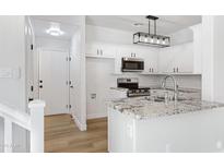 Bright white kitchen with granite countertops, stainless steel appliances, and modern lighting fixture at 1563 S Longspur Ln, Gilbert, AZ 85296