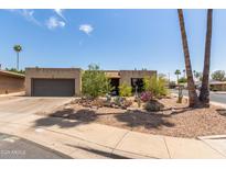 Charming single-story home with desert landscaping, attached garage, and palm trees on a sunny day at 1715 S Cholla St, Mesa, AZ 85202