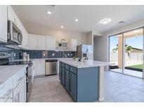 Modern kitchen with stainless steel appliances, blue tiled backsplash, an island with a marble countertop, and a sliding glass door at 29891 N Desert Angel Dr, San Tan Valley, AZ 85143