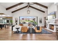 Bright living room with high ceilings, exposed beams, fireplace, and sliding glass doors to the backyard at 13750 E Yucca St, Scottsdale, AZ 85259