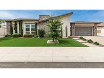 Contemporary home featuring lush landscaping, a well-manicured lawn, and modern architectural details at 13850 W Weaver Ct, Litchfield Park, AZ 85340