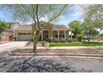 Charming home with stone accents, a two-car garage, a covered porch, and a well-maintained front yard at 20421 W Legend Trl, Buckeye, AZ 85396
