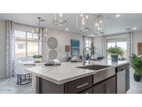 Bright kitchen boasts a large island with stainless steel sink and modern lighting at 20961 W Pasadena Ave, Buckeye, AZ 85396