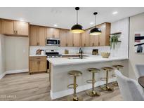 Beautiful kitchen features wood cabinets, stainless steel appliances, a white countertop island with seating, and pendant lighting at 2123 E Radcliffe Dr, Tempe, AZ 85283