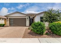 Charming single-story home with a brick driveway, lush landscaping and a two-car garage at 22568 E Rosa Rd, Queen Creek, AZ 85142