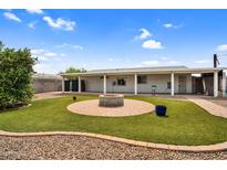 Cozy backyard featuring a brick fire pit, artificial grass, and a covered patio area, ideal for outdoor entertaining at 701 S 92Nd St, Mesa, AZ 85208