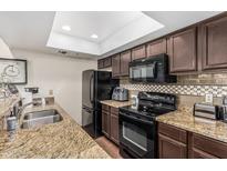 Updated kitchen features granite counters, stylish tile backsplash, and black appliances at 7777 E Main St # 143, Scottsdale, AZ 85251