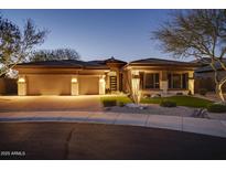 Stunning home featuring a three-car garage, stone accents, desert landscaping, and modern design at twilight at 7904 E Quill Ln, Scottsdale, AZ 85255