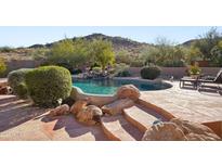 Inviting pool with rock features and lush landscaping in a serene backyard setting at 11255 S San Adrian Ln, Goodyear, AZ 85338