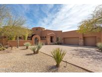 Beautiful southwestern home with desert landscaping, arched entry, and spacious driveway leading to a three-car garage at 35195 N 98Th St # 85, Scottsdale, AZ 85262