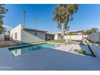 A refreshing pool with a modern deck and a covered lounge area enhances the backyard of this property at 4033 W Sharon Ave, Phoenix, AZ 85029
