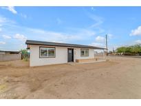 Charming single-story home with fresh white paint, new black roof, and a spacious dirt front yard under a bright blue sky at 546 N 96Th Pl, Mesa, AZ 85207