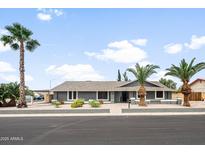 Charming single-story home featuring desert landscaping and mature palm trees at 1408 N 62Nd Pl, Mesa, AZ 85205
