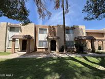 Exterior view of townhome featuring a covered entryway, neutral toned facade, well-maintained lawn and mature trees at 7126 N 19Th Ave # 108, Phoenix, AZ 85021