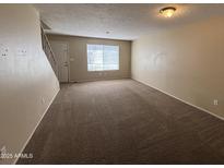 Inviting living room featuring neutral walls, carpet, and natural light from the window and a stairway to the upper level at 7126 N 19Th Ave # 108, Phoenix, AZ 85021