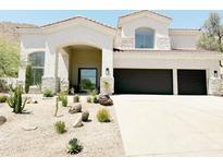 Charming single-Gathering home featuring a desert landscape, covered porch, and a spacious three-car garage at 11446 E Sweetwater Ave, Scottsdale, AZ 85259