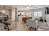 Inviting living room featuring modern furnishings, herringbone floors, and a view of the adjacent kitchen area at 13540 N 87Th Dr, Peoria, AZ 85381