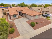 Charming single-story home showcasing a tile roof, desert landscaping, and a spacious driveway for ample parking at 14417 N 151St Dr, Surprise, AZ 85379