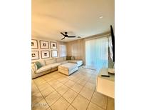 Bright living room featuring tile floors, a ceiling fan, and a large sectional sofa at 18575 W Vogel Ave, Goodyear, AZ 85338