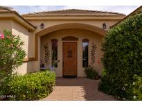 Inviting front entrance with a wooden door, arched entryway, and lush landscaping at 2203 E Tonto Pl, Chandler, AZ 85249
