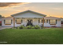 Charming one-story home with a lush green lawn and welcoming front porch with a rocking chair at 7607 N 17Th Ave, Phoenix, AZ 85021