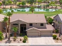 Stunning home showcasing a well-manicured lawn, mature palms and a view overlooking a lush golf course at 21841 N Ingram Ct, Maricopa, AZ 85138