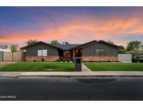 Charming single-story home with a brick accent, green lawn, and beautiful dusk sky at 2619 E Jerome Ave, Mesa, AZ 85204